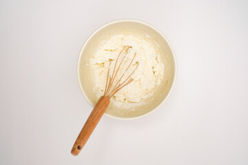 Raw dough with whisk for pastries and flour isolated on white background. Top view. Flatlay.