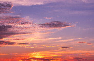 Sky background at sunset with colorful orange clouds of sunlight on the blue evening sky. The beauty of nature. Sky at sunset. Sunset. Beautiful clouds at sunset