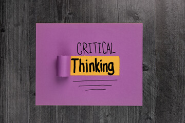 Critical Thinking handwritten on purple and yellow paper flat lay background