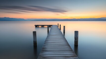 Fototapeta premium Wooden pier extending over calm water at sunset. background with beautiful landscape
