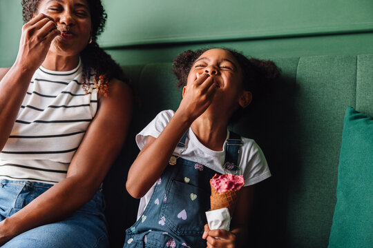 Happy mother and daughter laughing and enjoying ice cream together