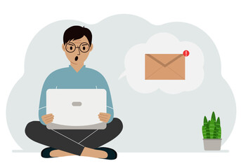 A man sits cross-legged working with a laptop and opens an email. The concept of education, work, correspondence.