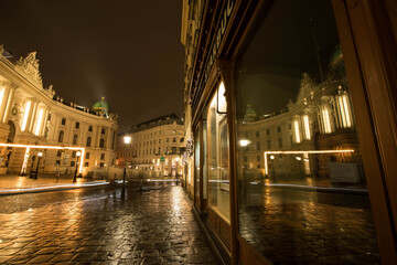 Vienna, Austria: Michaelaplatz in the center of Vienna at night, reflected in the window of a...