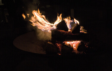 fire burning in fire pit (logs wood flame flames rising hot summer recreation) back yard patio