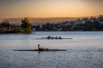 Silhouette of people enjoying rowing on Saint Roque Lake in Villa Carlos Paz at sunset