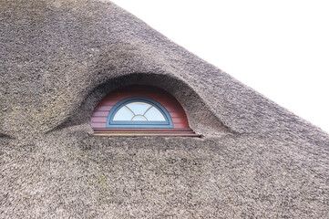 original windows in the attic of a house with a roof made of reeds and straw