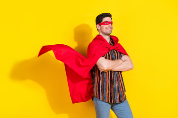 Portrait of nice young man folded arms look empty space wear superhero costume isolated on yellow color background