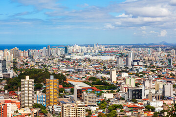 Fototapeta premium Aerial view of Vila Velha from Convento da Penha on a sunny day, highlighting Praia da Costa and Itapuã neighborhoods with the blue ocean in the background. Perfect blend of urban and coastal beauty.
