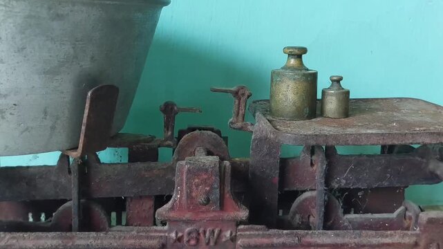 Old rusty analog scales placed on the floor and against a blue wall background
