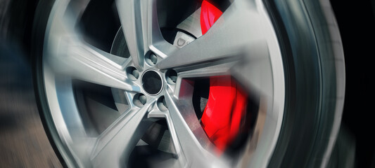 Fast moving car wheel with red brake close up