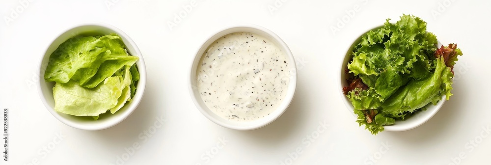 Poster A bowl of fresh lettuce, a bowl of creamy ranch dressing, and a bowl of mixed green leaves, perfect for a healthy salad.