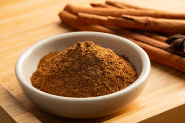 Close up cinnamon powder in a bowl with cinamon stick.