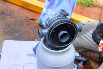 Worker installing sand filter system tank equipment for cleaning swimming pools