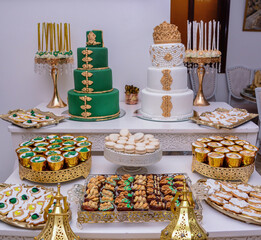 Two wedding cakes with a Moroccan theme on the festive table with plenty of snacks on the side