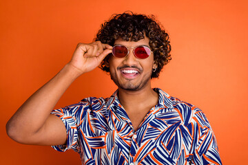 Fototapeta premium Photo portrait of handsome young man touch sunglass dressed stylish colorful garment isolated on orange color background