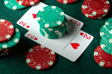 Multicolored chips and playing cards with a combination of one pair on the table. The concept of a successful win in the club