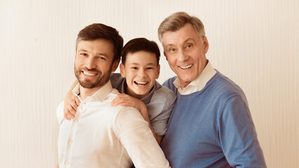 Male Family Portrait. Smiling Boy With Father And Grandfather Hugging Looking At Camera Standing Against White Background. Panorama