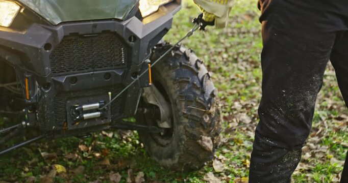 Young Man Pulling Out Winch Cable From ATV