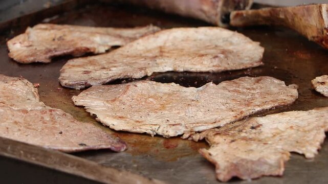 Carne asada cocinandose a fuego lento en la parrilla