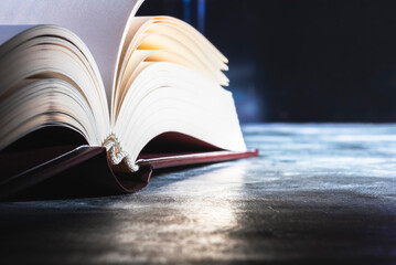 Opened hard cover book pages with toned dark background, close-up view