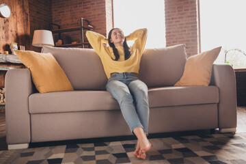 Full length photo of nice teen lady sit couch relax hands behind head dressed yellow garment spend...