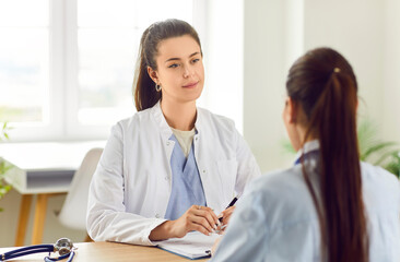 Obraz premium Attentive woman doctor or nurse providing medical consultation and support to a patient in the hospital. Engaging in a helpful conversation to ensure comprehensive healthcare and patient care.