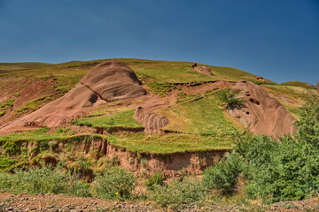 Mountains of volcanic origin with elements of hardened lava, overgrown with soil and grass.