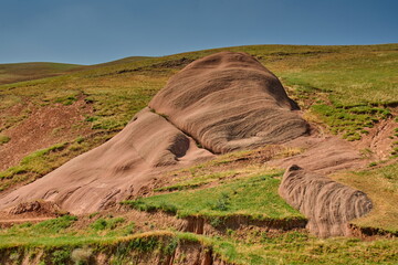 Mountains of volcanic origin with elements of hardened lava, overgrown with soil and grass.