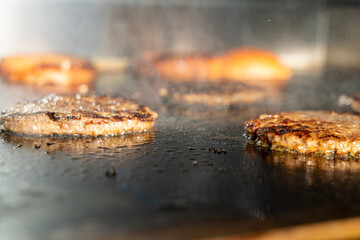 Make burgers on the grill restaurant. Burgers cooking on a gas grill, how to make a burger step by step. A person using a spatula to cut meat. a person cutting meat on a grill with a knife