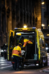 dos técnicos en emergencias sanitarias paramédicos suben a un paciente encamillado a una...