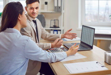 Positive business colleagues, man and woman, collaborating in an office during work meeting, engaged in a discussion while using a laptop for accounting purposes, showing teamwork and collaboration.