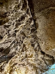 A close-up of rough, textured rock inside a mine, showcasing layers of mineral deposits and weathered stone. The image captures the raw beauty and complexity of underground geology.