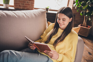 Photo portrait of nice teen lady sit sofa read book dressed yellow garment spend pastime spacious...