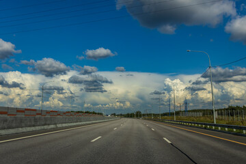 Fototapeta premium A long, empty highway with a few trees in the background