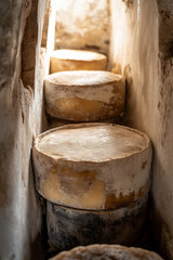 Naklejka premium Aged cheese wheel stored in a cellar with a natural rind, highlighting the artisanal craftsmanship.