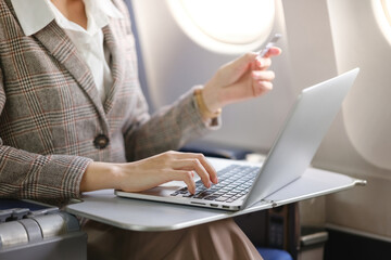 A woman is sitting on a plane with a laptop open in front of her