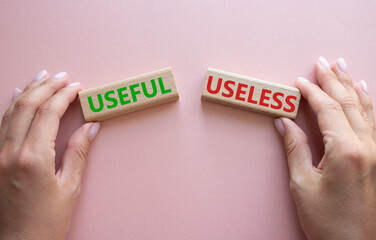 Useful or Useless symbol. Concept word Useful or Useless on wooden blocks. Businessman hand. Beautiful pink background. Business and Useful or Useless concept. Copy space