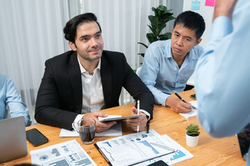 Diverse group of business analyst team analyzing financial data report paper on office table. Chart and graph dashboard by business intelligence analysis for strategic marketing planning Habiliment