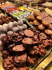 A vibrant food market stall in Barcelona, Spain, overflowing with colorful sweets. Delicious macarons, nut-based treats, almonds, and cookies create a captivating and mouthwatering.
