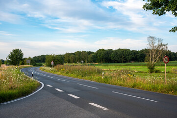 Fototapeta premium Asphalt road with intersection at the German countryside around Kirchseelte, Lower Saxony, Germany
