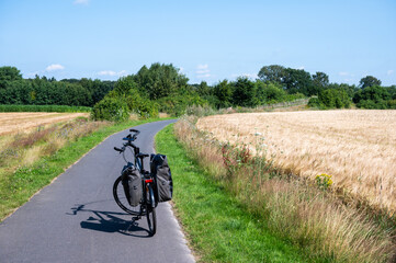 Trekking bike with paniers standing on an asphalt road at the German countryside around Lastrup,...