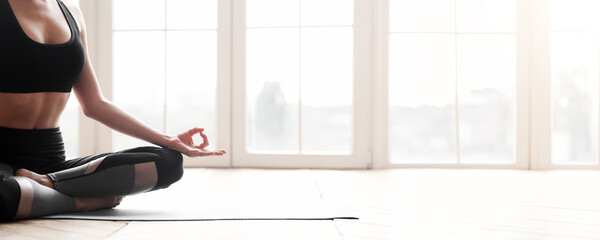 Balance, meditation, relaxation concept. Cropped photo of fit woman meditating during yoga class over panoramic windows background, panorama with copy space