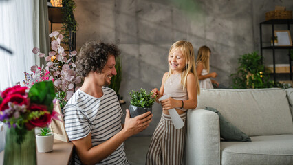 Obraz premium Father and daughter gardener or florist take care of plant with spray