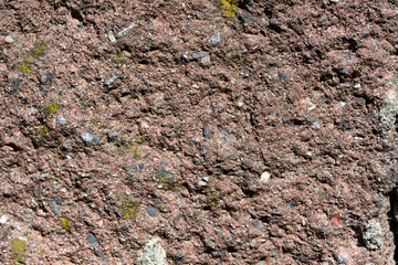 Rough textured brown stone surface with moss
Close-up of a rough brown stone surface with small patches of moss, showing its uneven texture and natural earthy tones.

