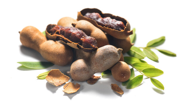 Tamarind tropical fruits isolated on white background. Fresh Tamarind pods with leaves (Tamarindus indica, Indian date), healthy vegan food close up