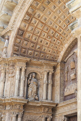 An ornate architectural detail of a historic building. Sculpted figure and intricate stone carvings under a richly decorated coffered ceiling. Cathedral of Mallorca, Palma de Mallorca
