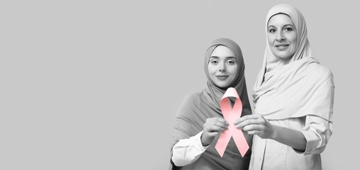 Muslim women with pink ribbon on light background with space for text. Breast cancer awareness...