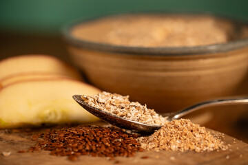 A spoon with cereal, in the background a bowl and apples