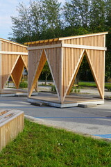 Modern wooden arbor, gazebo. Green foliage tree on the back. Sunny day during summer time. Pirita, Tallinn, Estonia, Europe. July 2024