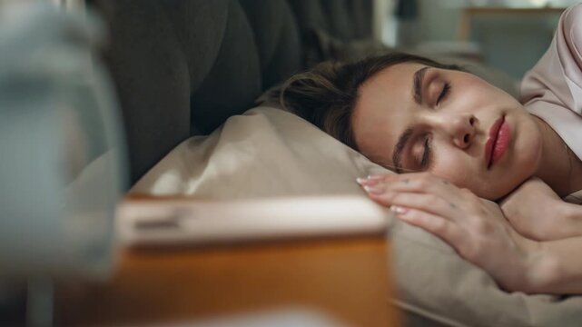 Peaceful lady sleeping bed at morning closeup. Closed eyes woman ignoring alarm